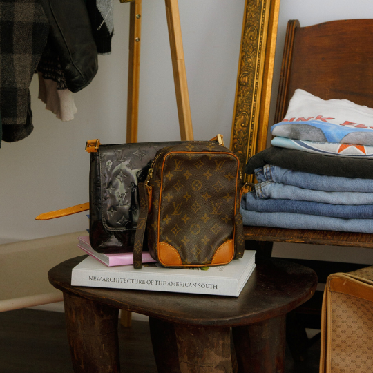 a collection of handbags, jeans, t-shirts set on furniture