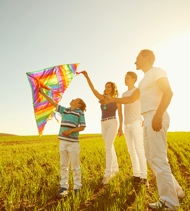 a family of 4 playing with kites in a field