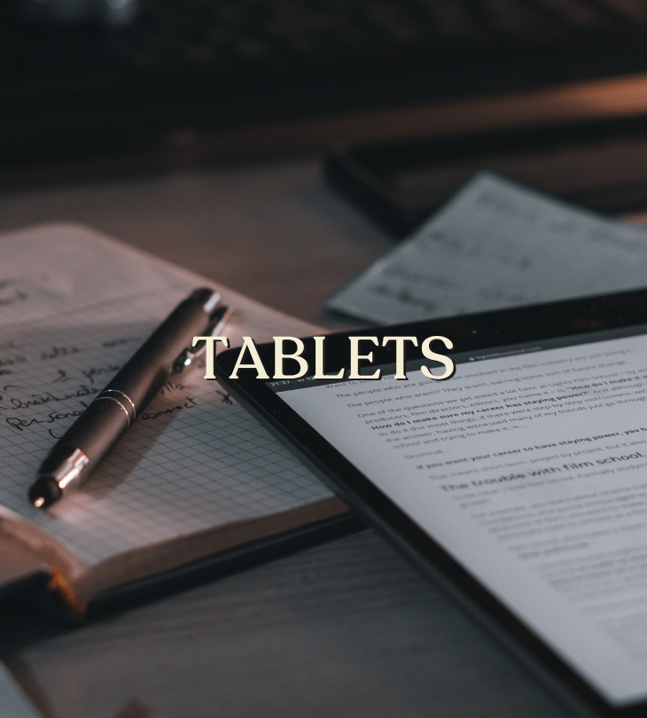 Tablets: a tablet displaying text beside an open notebook and pen.