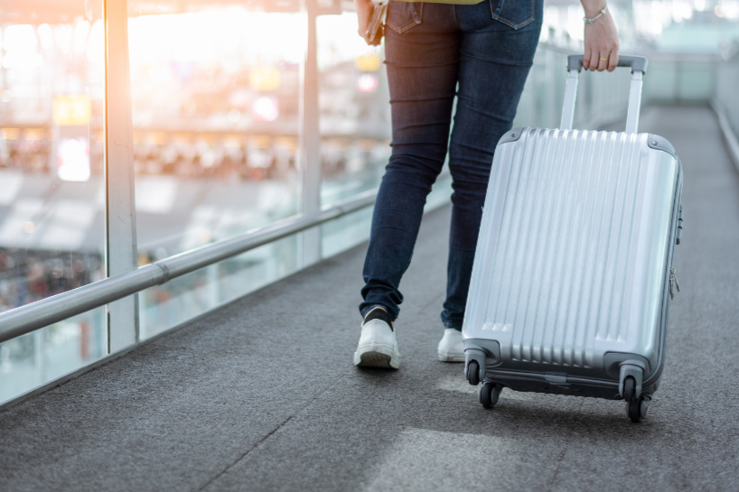 a person rolling a silver suitcase walking 