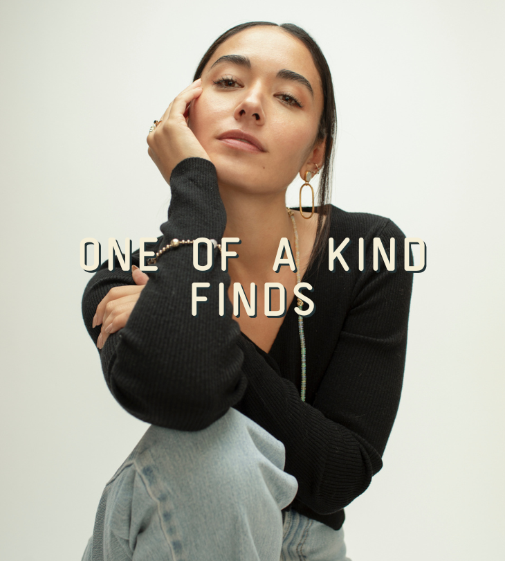 Woman wearing a black sweater with text 'ONE OF A KIND FINDS' on a plain background