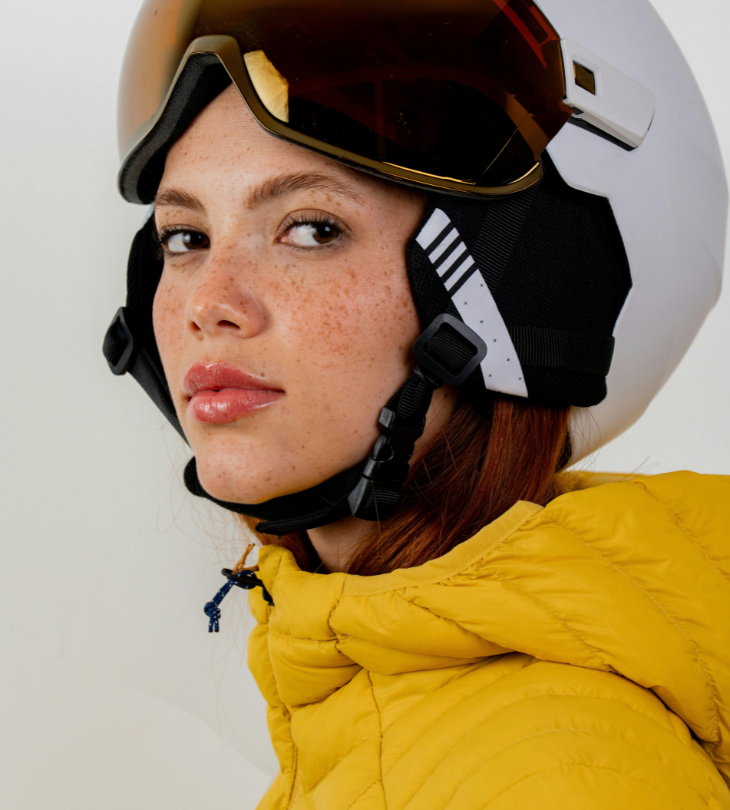a woman wearing ski helmet and yellow puffer jacket. 