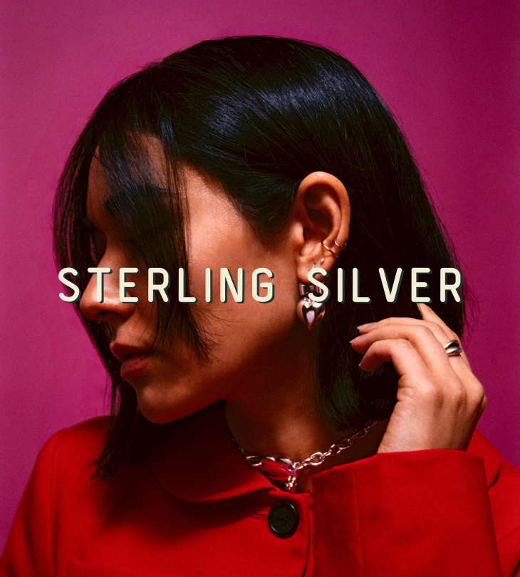 Person wearing jewelry with 'STERLING SILVER' text on a pink background