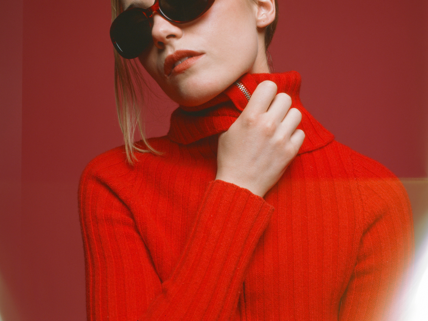 Person wearing a red turtleneck sweater against a red background