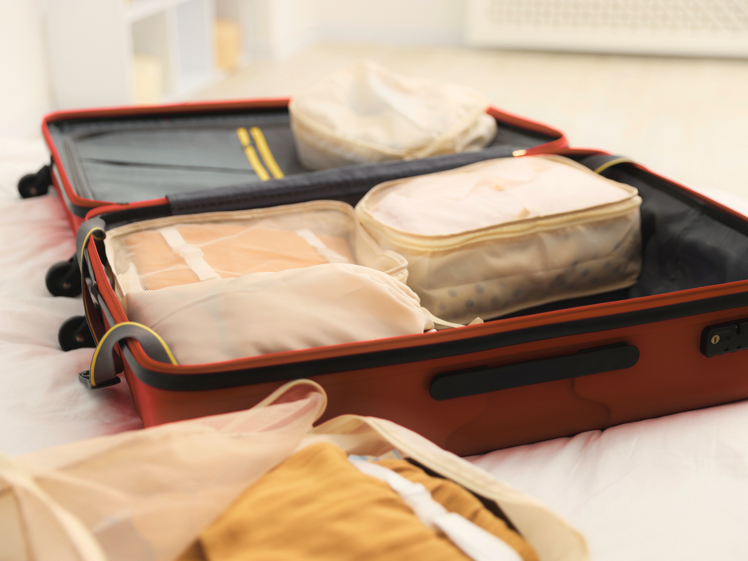 Open suitcase with packing cubes on a bed