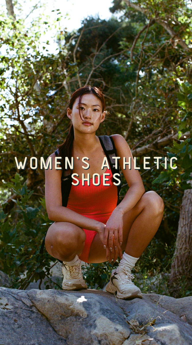 A woman crouching outdoors on rocks among trees, wearing a red athletic tank top, matching shorts, white socks, and beige athletic shoes. Large text across the center reads 'WOMEN'S ATHLETIC SHOES'.