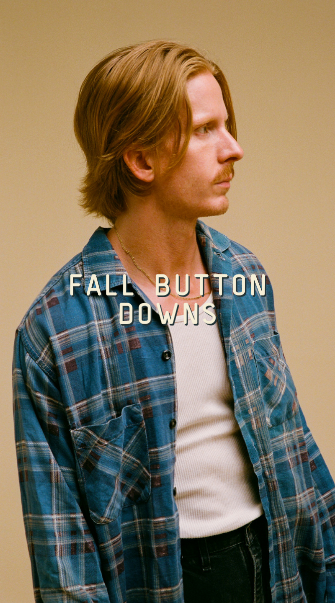 A man with light brown hair is shown in profile wearing a blue and red plaid button-down shirt over a white t-shirt, with the text 'FALL BUTTON DOWNS' overlaid across the center.
