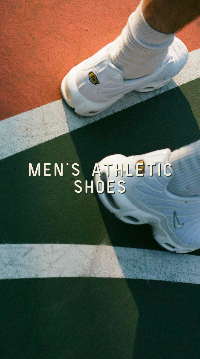 A top-down view of a person wearing white athletic shoes and white socks on a green and white court-like surface with orange-red pavement visible. Large overlaid text reads 'MEN'S ATHLETIC SHOES'.