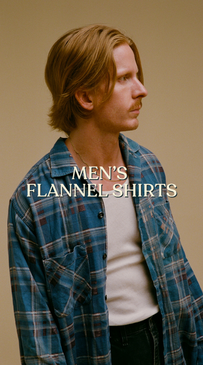 Men’s flannel shirts: Model wearing an open blue plaid flannel shirt over a white top.

