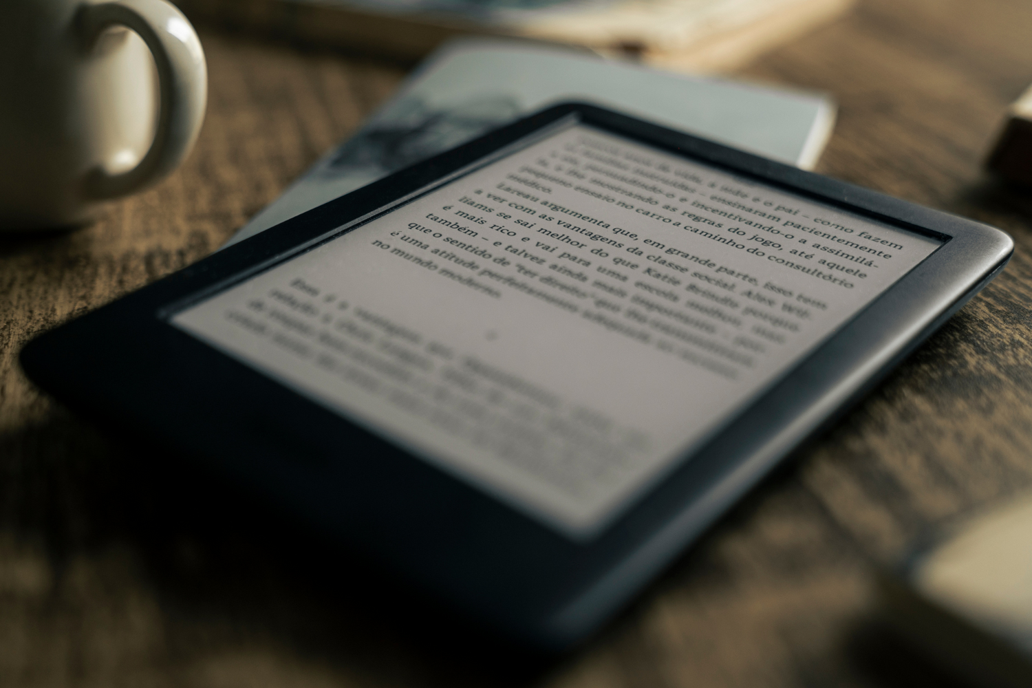 a wood table with e-reader and a book