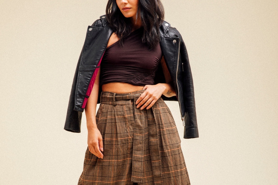 a woman in a leather jacket and brown plaid skirt
