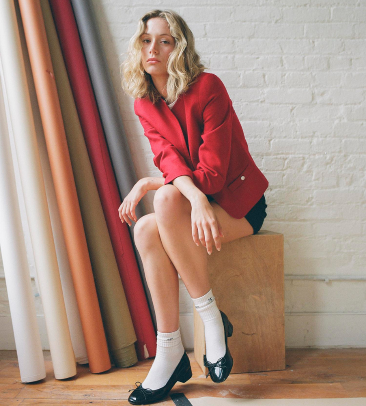 a person wearing a red jacket sitting on a stool